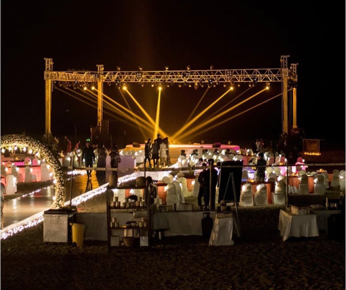 Outdoor dinner under a truss with warm string lights